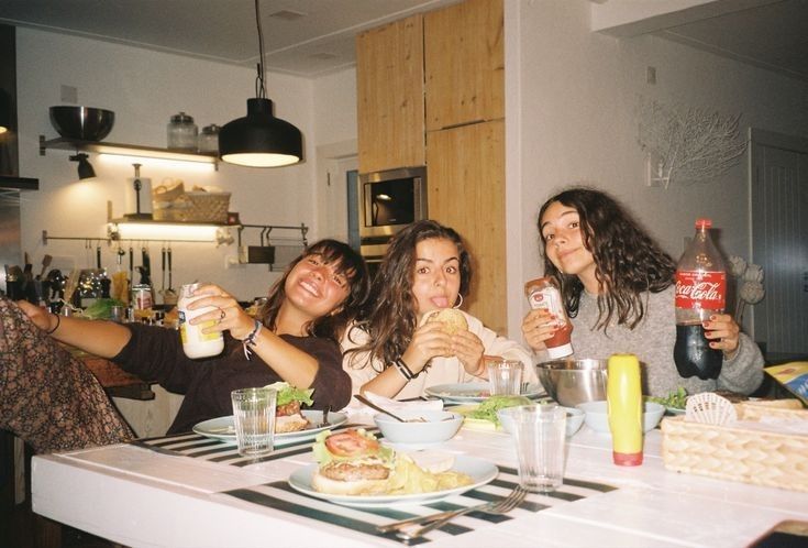 four women sitting at a table with food and drinks