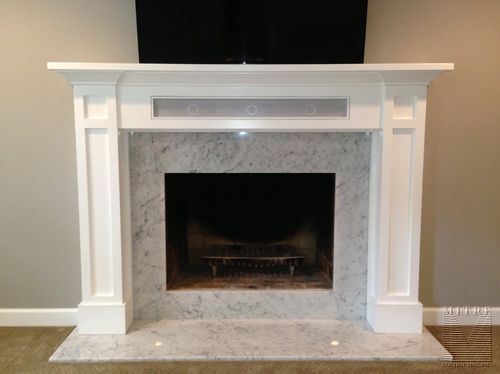 a white fireplace with a tv above it