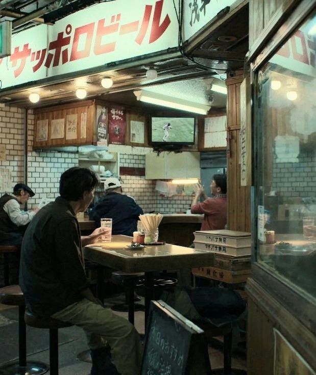 people sitting at tables in a restaurant with menus on the wall and signs above them