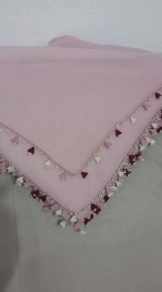 a pink and grey blanket with tassels on it's edges is shown