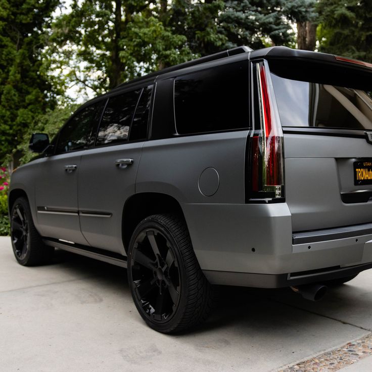 a silver suv parked in front of some trees