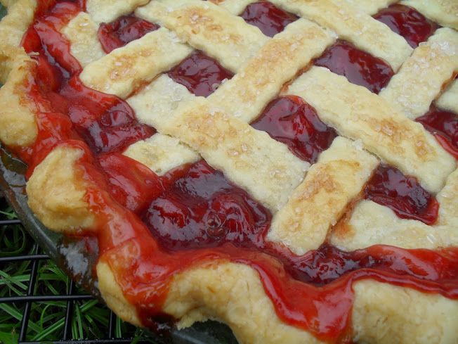 a pie with red and white toppings sitting on top of a metal grill grate