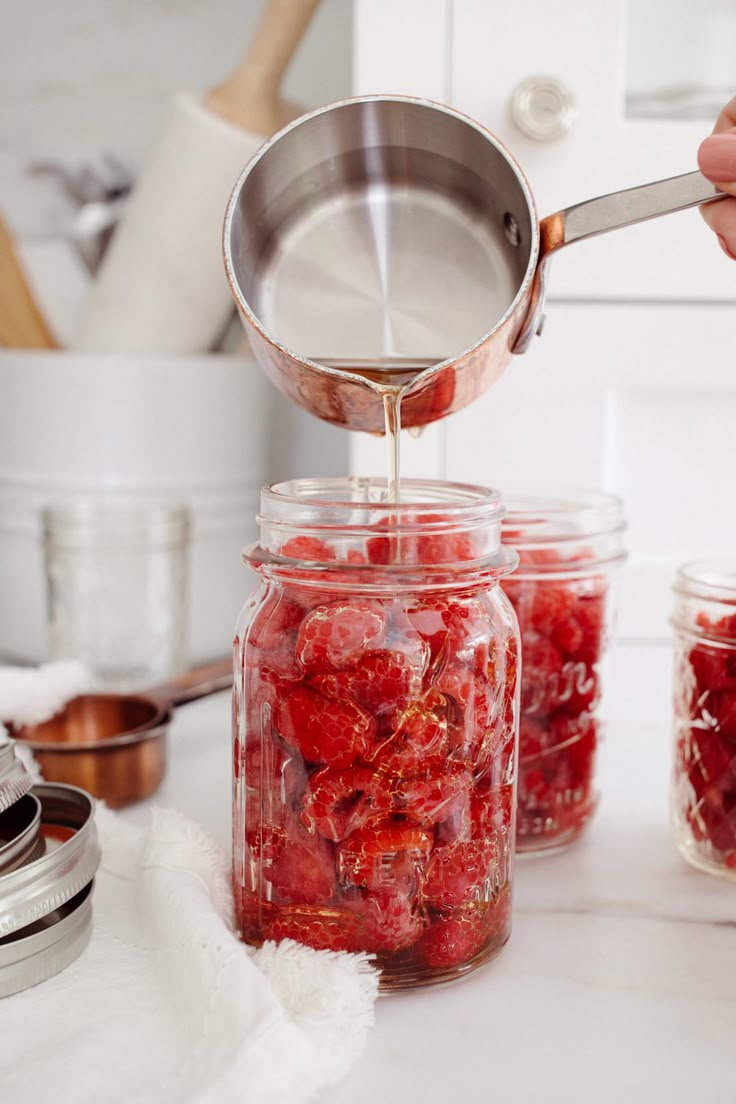 a person is pouring sugar into jars filled with strawberries