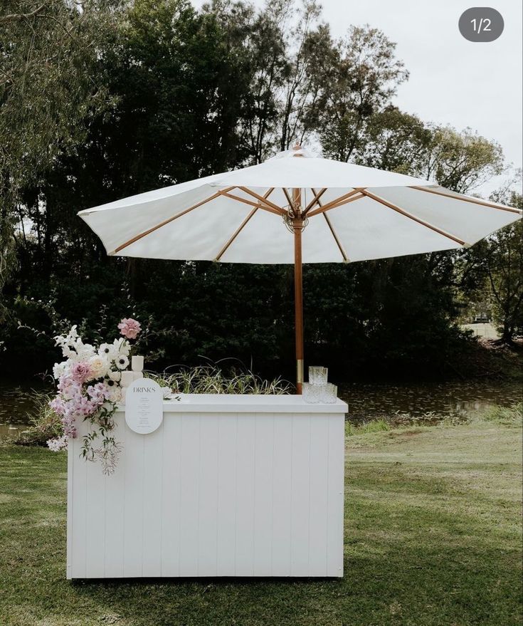 an umbrella is over a small bar in the grass