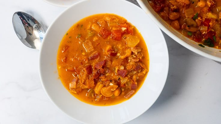 there is a bowl of soup on the table next to another bowl with food in it