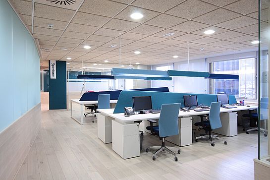 an empty office with blue and white desks in the middle of it's walls