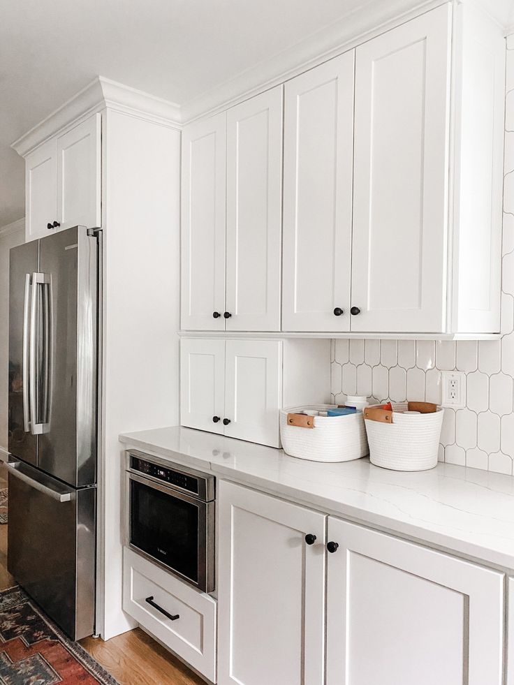 a kitchen with white cabinets and stainless steel appliances, including a refrigerator freezer in the center