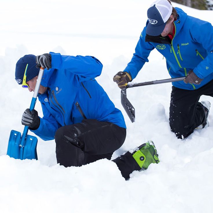 two men are shoveling snow with their skis