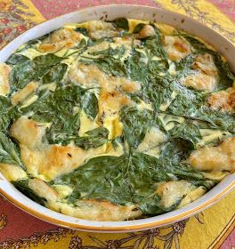 a casserole dish with spinach and cheese in it on a colorful table cloth