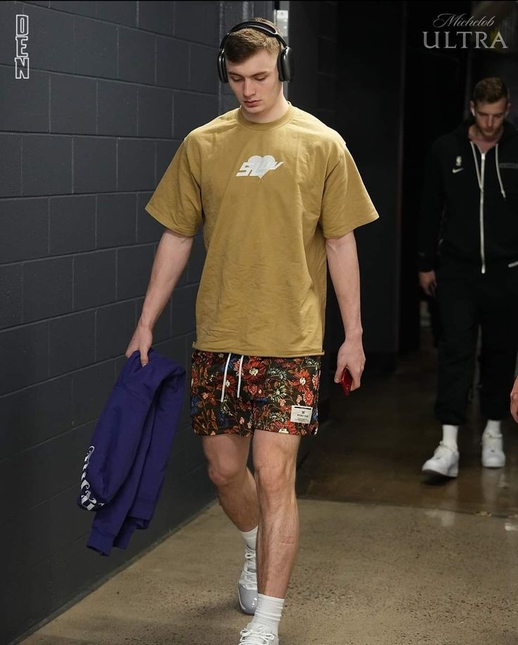 a man walking down a hallway wearing shorts