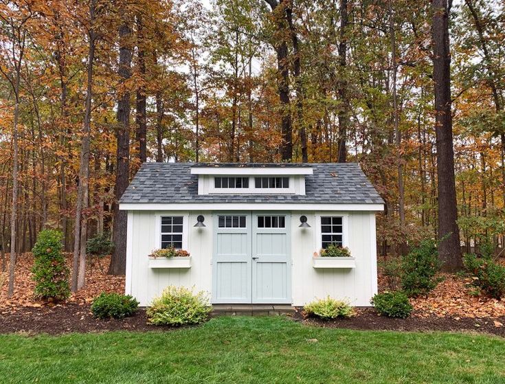 a small white shed sitting in the middle of a forest