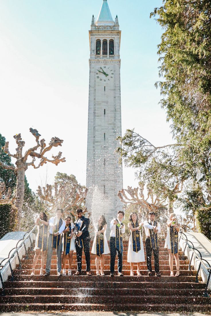 a group of people standing on steps in front of a clock tower