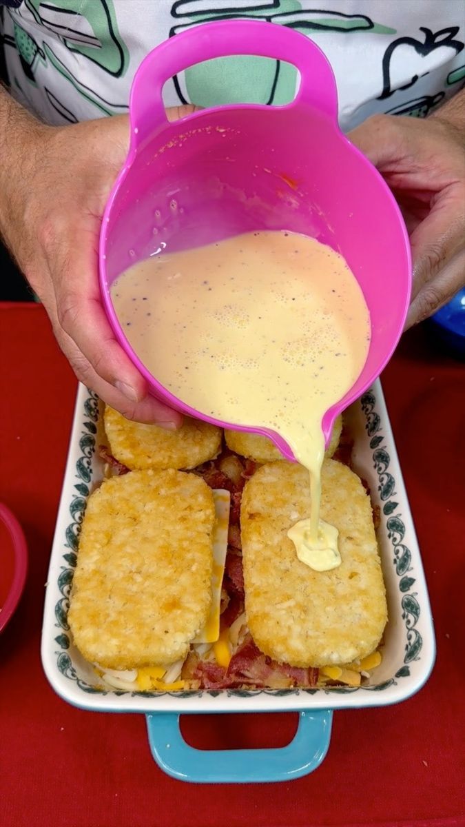 a person pouring sauce on some food in a container