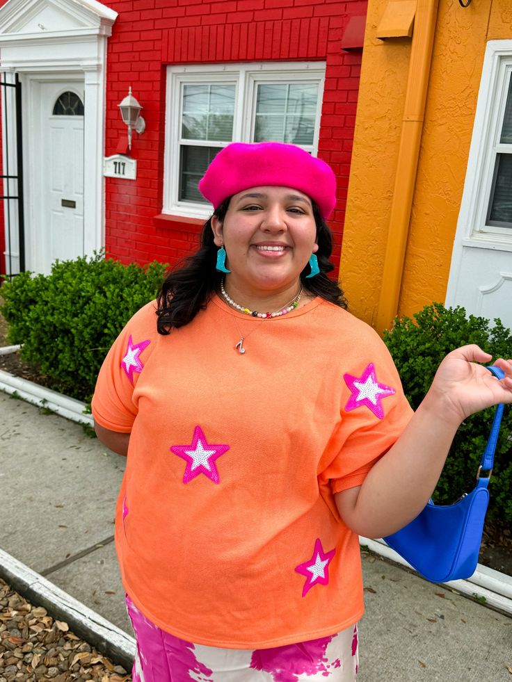 Bring on the glitz and glam with this oversized tee! This orange tee features pink stars that make you feel like a super star!!! Keep it casual with a pair of jeans or colorful pants, or dress it up with a pink skirt! This tee looks great with pinks, yellows, and blues! Oversized fit Style with jeans, colorful pants, or a cute skirt! This shade of orange looks great with pinks, blues, and yellows! True to size with an oversized fit 50% POLYESTER 37% COTTON 13% RAYON Imani is 5'3 and wearing a si Trendy Summer T-shirt With Star Patch, Spring Relaxed Fit T-shirt With Star Print, Relaxed Fit T-shirt With Star Print For Spring, Casual T-shirt With Star Print For Spring, Oversized Star Print Summer Tops, Cotton T-shirt With Star Patch For Summer, Trendy Oversized T-shirt With Star Print, Trendy Oversized Orange T-shirt, Oversized Orange T-shirt For Summer