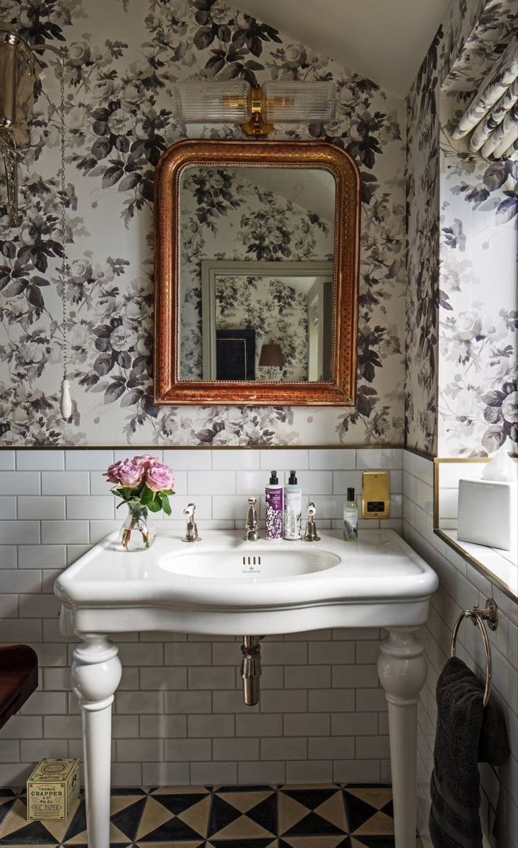 a white sink sitting under a mirror next to a wall mounted faucet in a bathroom