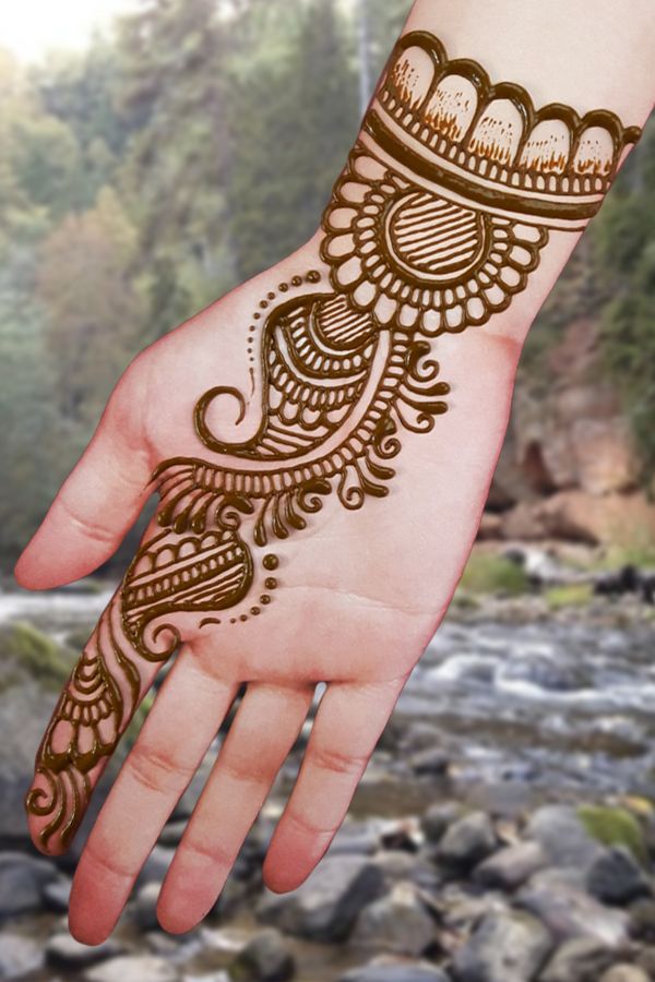 a hand with henna tattoo on it and rocks in the background, along with water