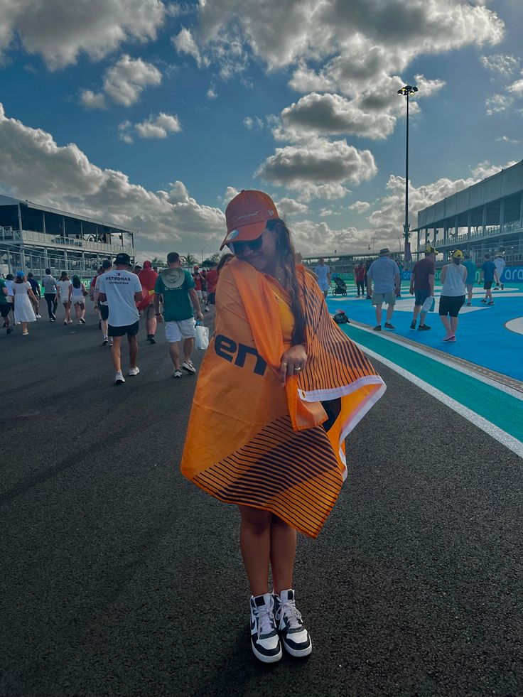 a woman in an orange raincoat is standing on the sidelines