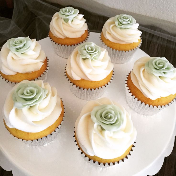 cupcakes with white frosting and green decorations on a cake platter, ready to be eaten