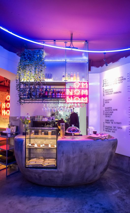 the interior of a restaurant with an unusual counter and seating area that is lit up at night