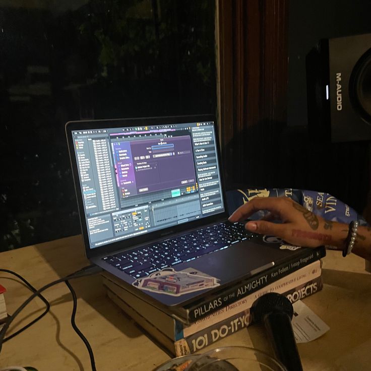 a person sitting at a table with a laptop on top of books and headphones