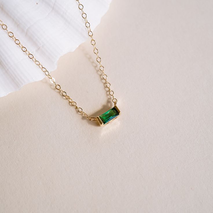 Unlock your beauty and mystique this May with the Tiny May Birthstone Necklace! Crafted with an emerald hued cubic zirconia, this exquisite charm captures the essence of love and rebirth. Showcase your passion for life and take a leap of faith - it's time to dream bigger than before! NECKLACE FEATURES: 16k gold plated emerald hued cubic zirconia birthstone charm 14k gold filled chain & findings Necklace comes with coordinating May birth month card Emerald Cut Jewelry With Si Clarity As Gift, Gift Cubic Zirconia Emerald Necklace, Cubic Zirconia Emerald Necklace For Gifting, Cubic Zirconia Emerald Necklace Gift, Everyday Emerald Birthstone Jewelry, Green Cubic Zirconia Necklace For Gift, Emerald Birthstone Pendant Necklace In Cubic Zirconia, Emerald Pendant Necklace With Cubic Zirconia Birthstone, Emerald Cubic Zirconia Birthstone Pendant Necklace