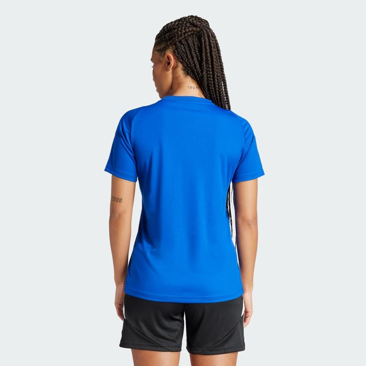 a woman wearing a blue shirt and black shorts is looking at the back of her body