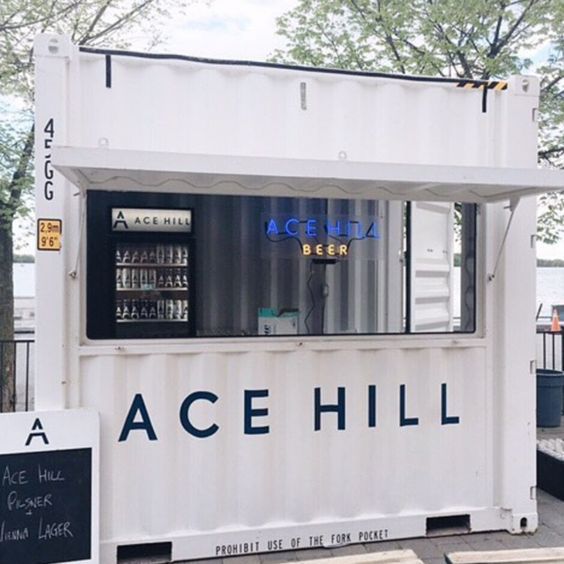 a white container with a sign that says acehill on it and some trees in the background