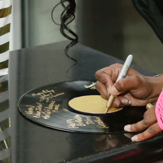 a woman is writing on a record with a pen and paper in front of her