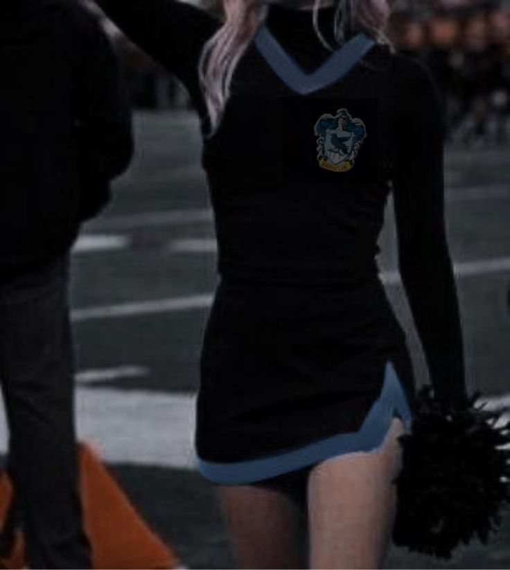 a woman dressed in cheerleader gear walking down the street with her hand on her hip