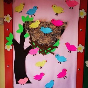 a bulletin board with birds on it and a bird nest in the tree next to it