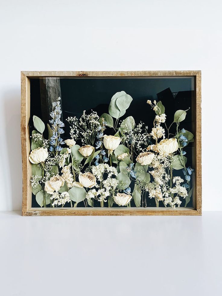 a wooden frame with flowers and greenery in it