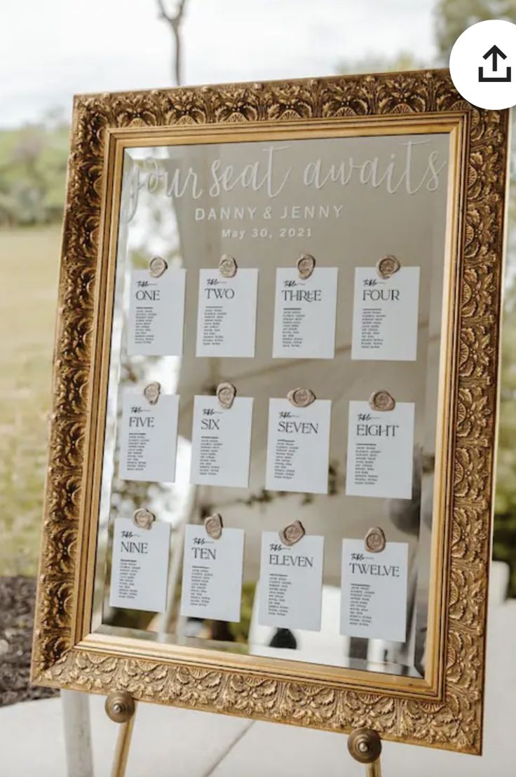 a gold framed mirror with seating cards on it