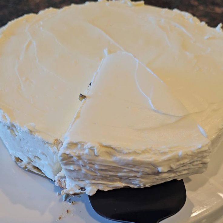 a white cake sitting on top of a plate with a black spatula in front of it