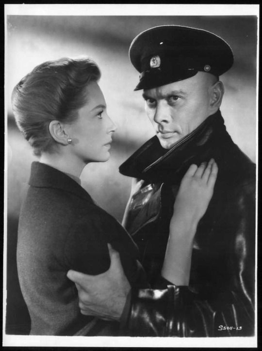 an old black and white photo of a man in uniform standing next to a woman