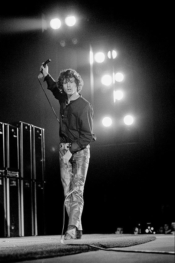 a man standing on top of a stage holding a skateboard in his hand with lights behind him