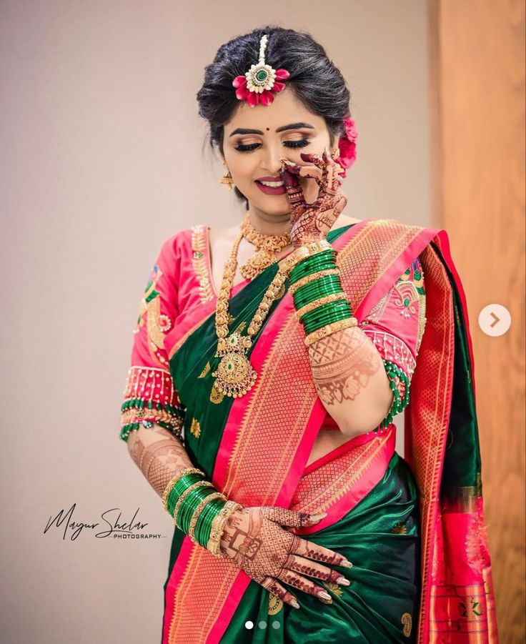 a woman in a green and pink sari holding her hands up to her face