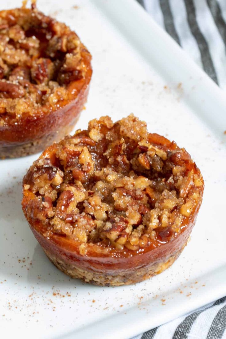 two desserts sitting on top of a white plate covered in nuts and crumbs