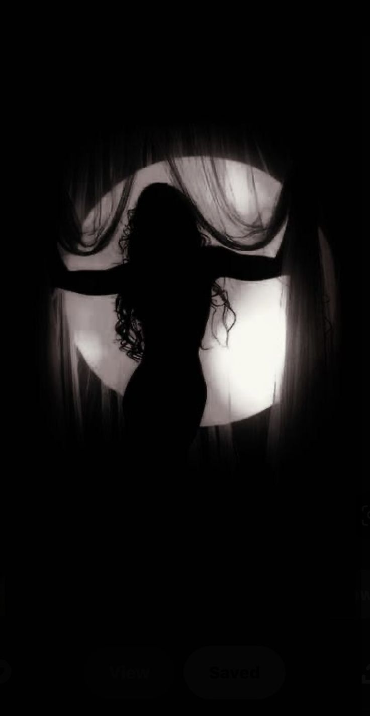 the silhouette of a woman standing in front of a window with her hair blowing in the wind