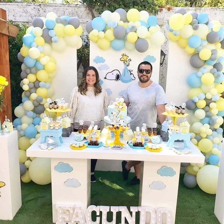 a man and woman standing in front of a table filled with desserts on it