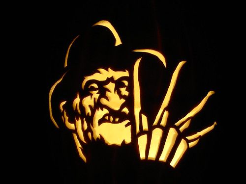 a carved pumpkin with an image of a man's face and hands on it