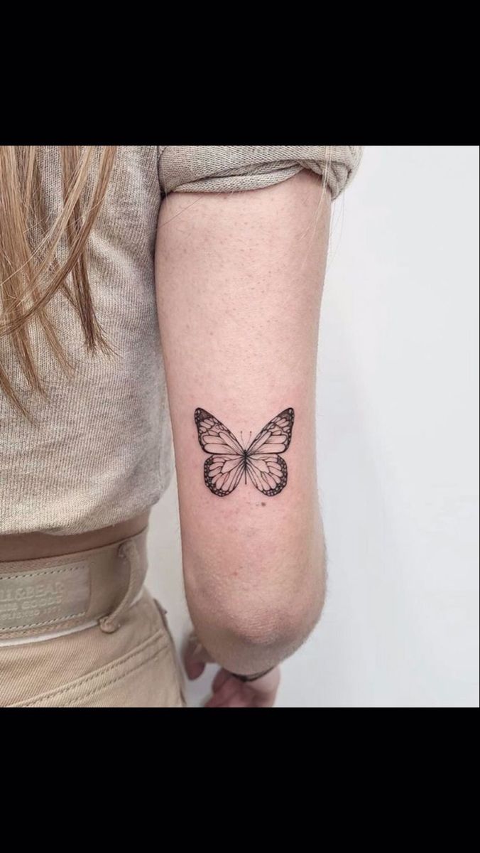 a woman's arm with a small butterfly tattoo on the left side of her arm