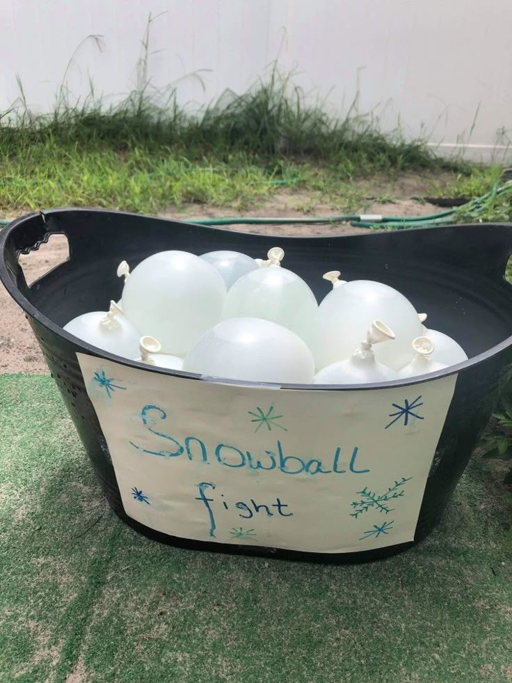 a black tub filled with white balloons on top of grass