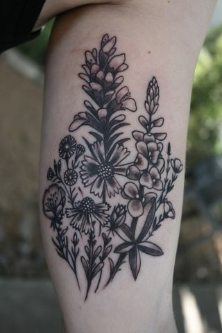 a black and white flower tattoo on the right arm, with small flowers in it