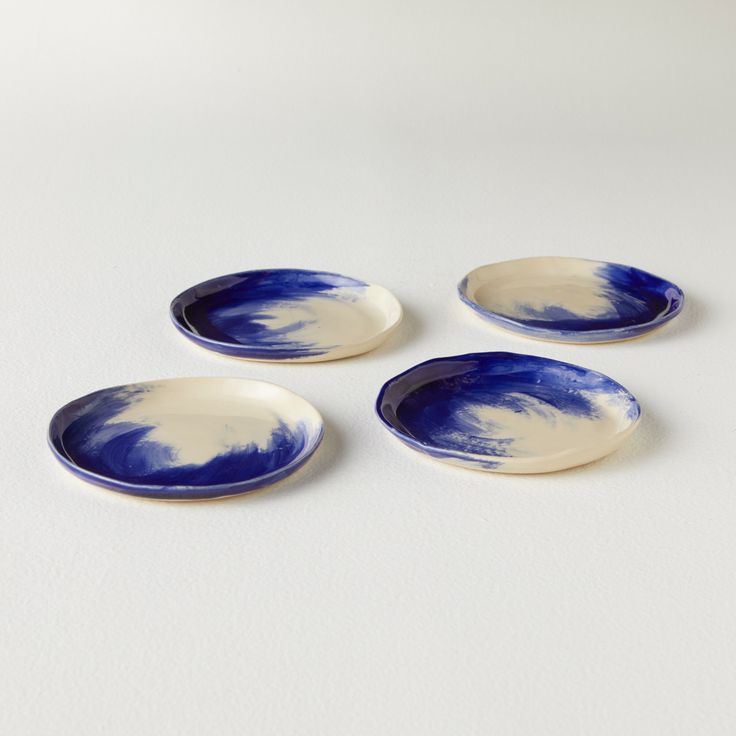 four blue and white plates sitting on top of a table