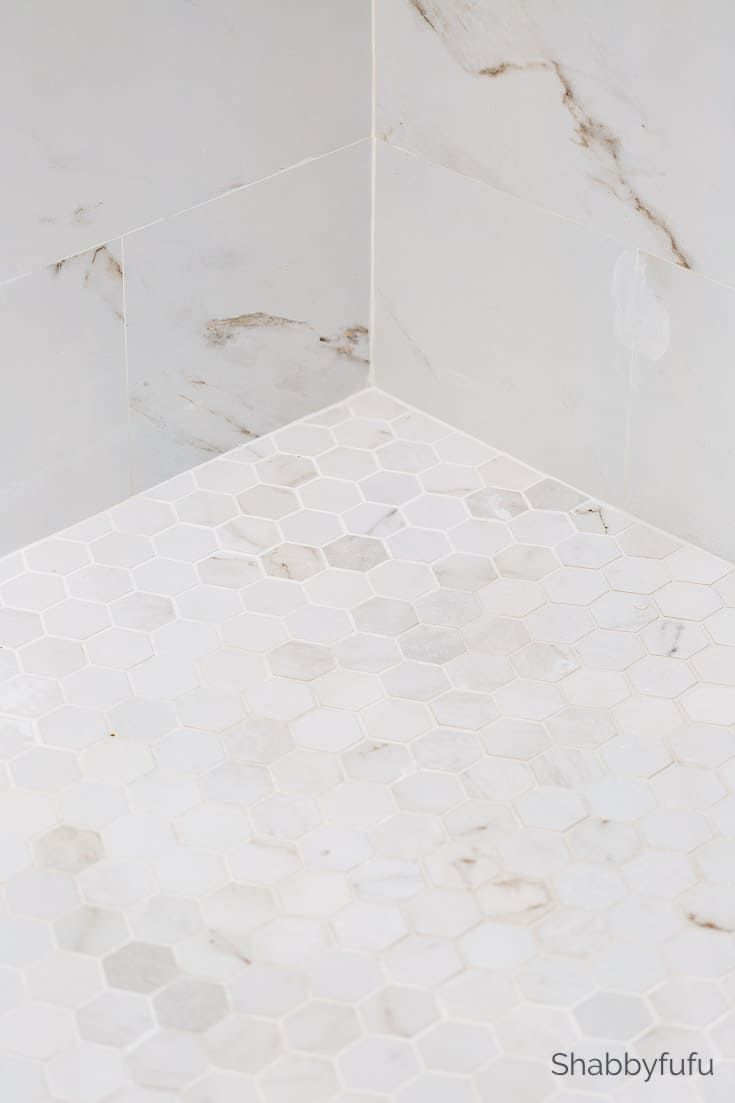 a white marble shower with hexagonal tiles