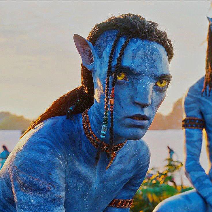 two people dressed as avatars with blue paint on their faces and hair, one is staring at the camera