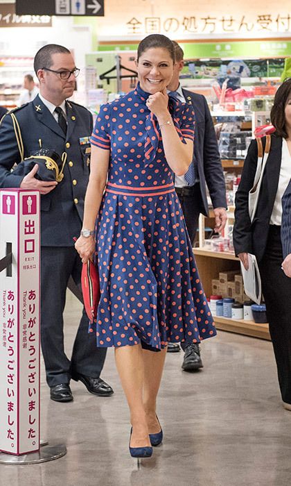 a woman in a polka dot dress is talking on her cell phone while walking through a store