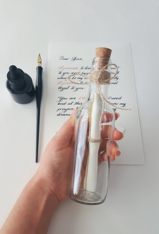 a person holding a message in a glass bottle