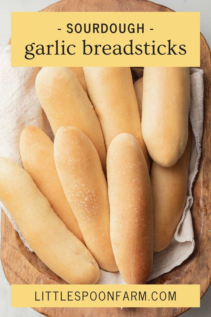 some breadsticks are in a wooden bowl on a table with the words, sourdough garlic breadsticks