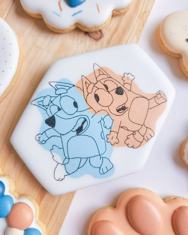 decorated cookies with cartoon characters on them sitting on a cutting board next to other cookies